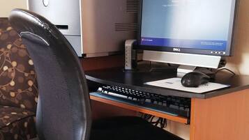 A wooden desk with a Dell desktop computer, a black office chair, and a printer.
