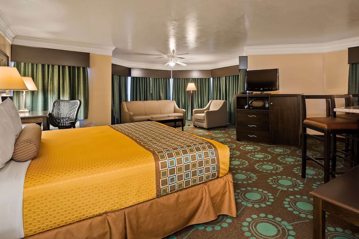 A hotel room with a bed, a desk, a chair, a television, and a minibar.