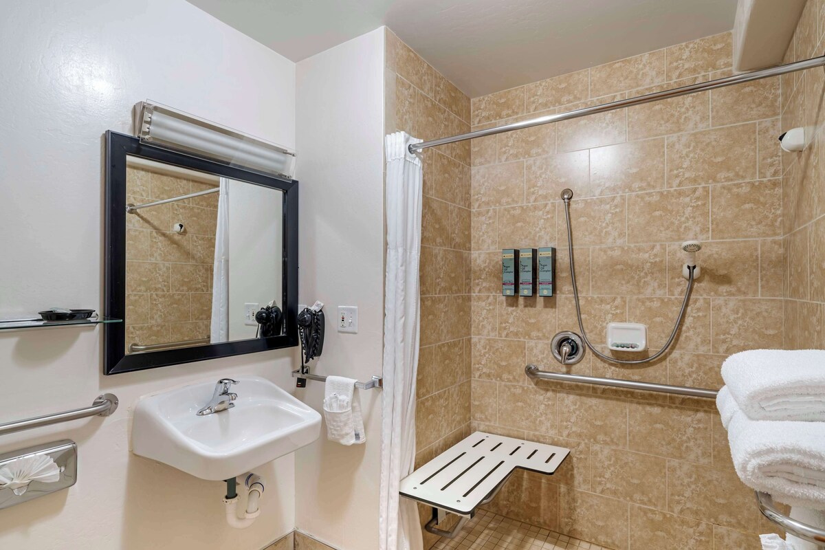 Une salle de bain équipée d’un lavabo, d’un miroir, d’une douche et d’un porte-serviettes.