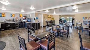 A spacious dining area with multiple tables and chairs, a kitchen area with appliances, and a counter.