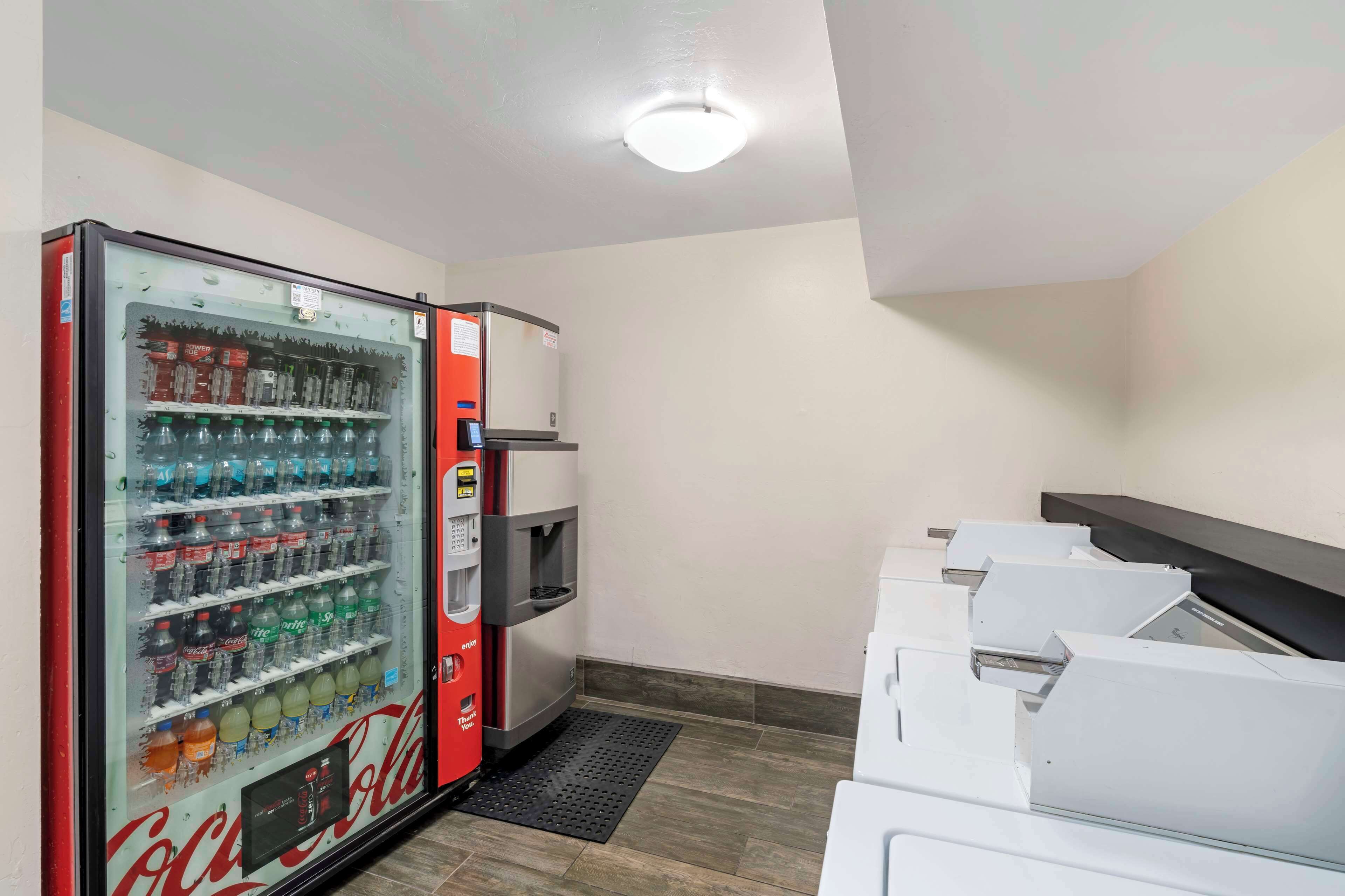 Un distributeur automatique orné du logo Coca-Cola, muni d’un point d’eau et d’une poubelle.