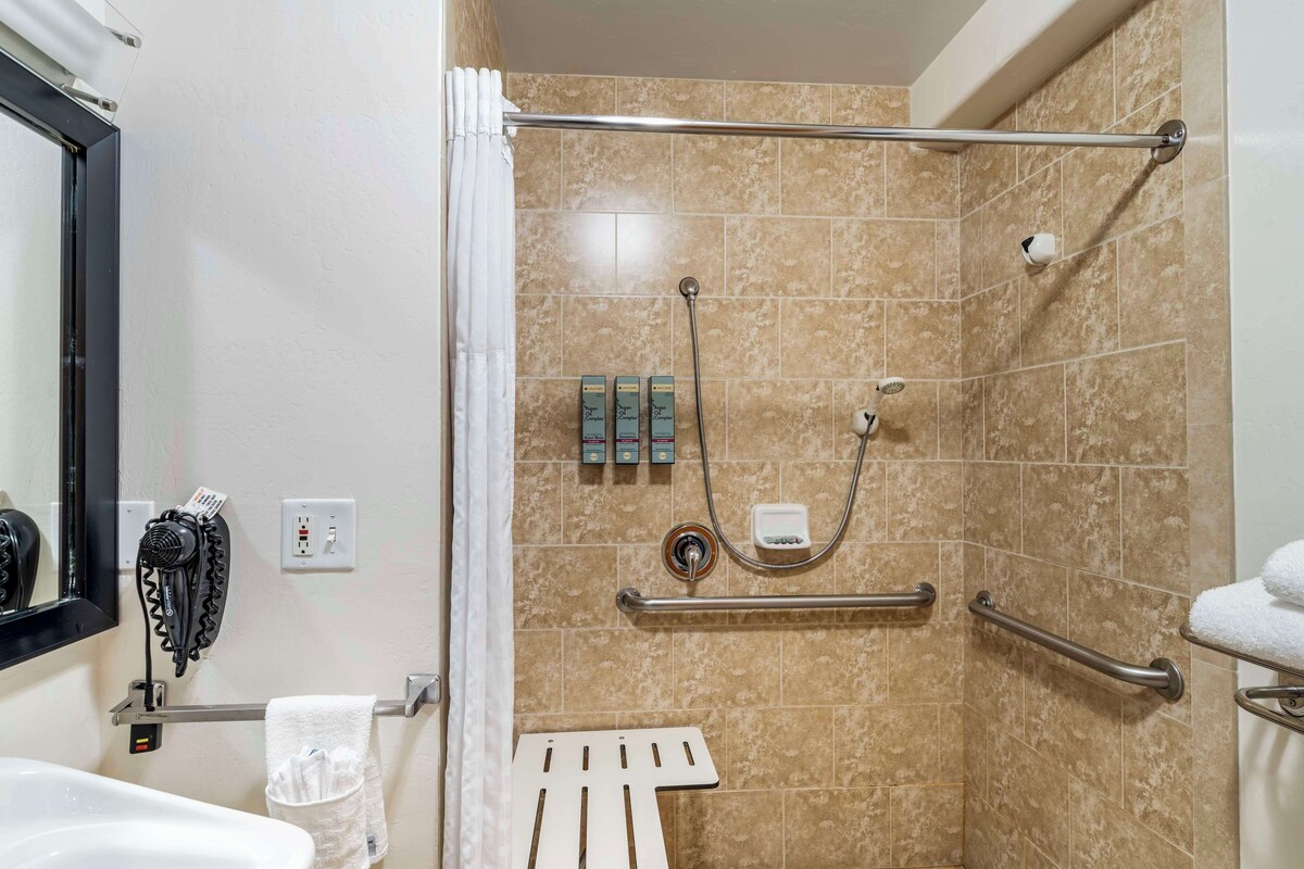 Un espace douche équipé d’un sèche-mains, d’un porte-serviettes et d’une barre d’appui.