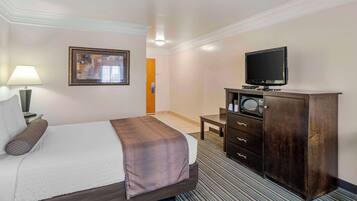A hotel room with a bed, a television, a desk, and a cabinet.