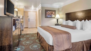 A hotel room with a bed, a TV, a desk, and a lamp.