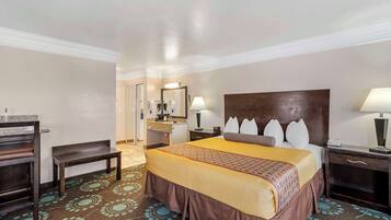 Habitación de hotel con una cama grande, un escritorio, una silla, un espejo y un baño a la vista.