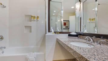 A modern bathroom with a bathtub, two sinks, and a large mirror.