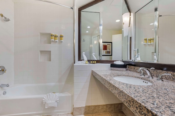 Un baño moderno con bañera, dos lavamanos y un espejo grande.