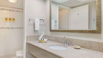 A bathroom with a white toilet, a sink with a zebra-striped mirror, and toiletries on the wall.
