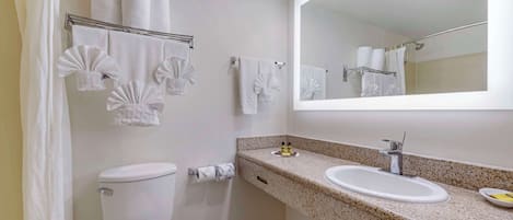 Un baño con inodoro, lavamanos y perchero para toallas.