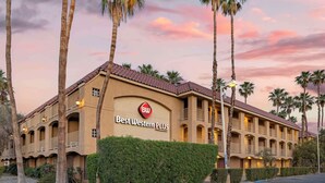 A hotel with a sign reading "Best Western PLUS" and a red logo. It features a multi-story structure with balconies and a tiled roof.