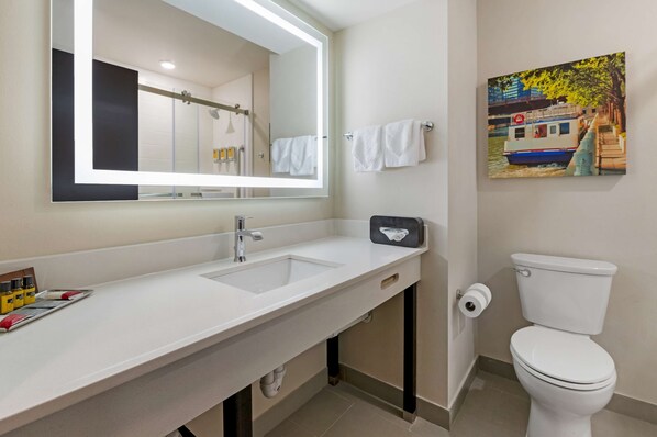 Un baño con un lavamanos blanco, un espejo, un inodoro y un cuadro de un barco en la pared.