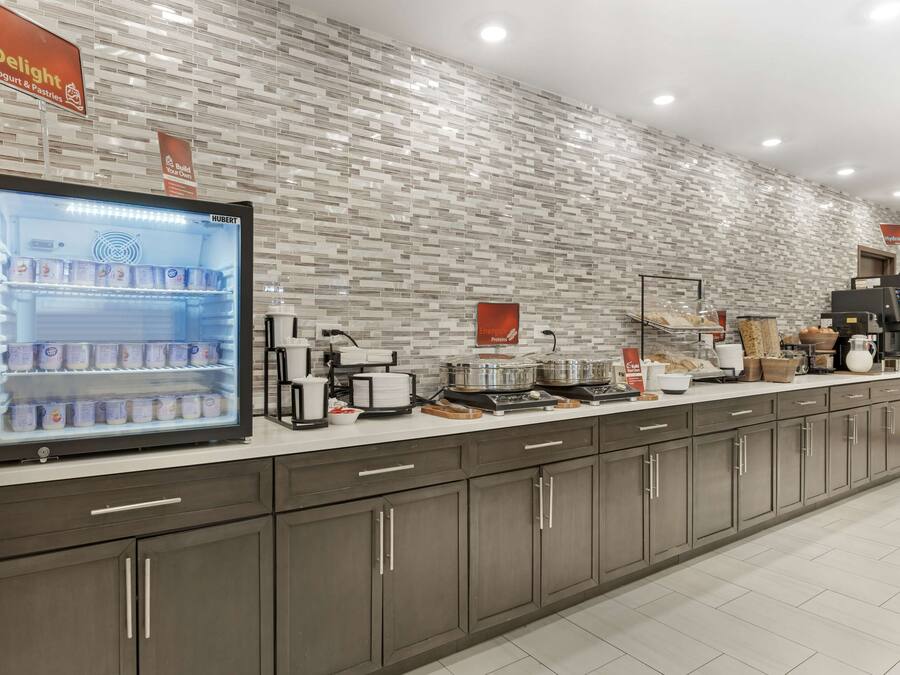A modern kitchen with a built-in refrigerator, coffee machines, and a display of baked goods.
