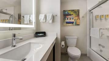 Een moderne badkamer met een wit wastafelmeubel, een toilet en een douche met glazen wanden.