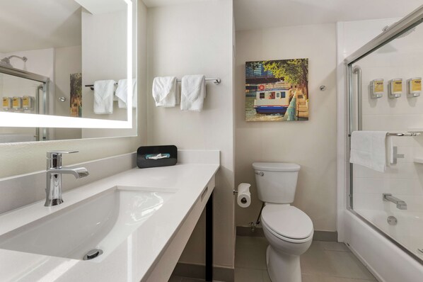 Un baño moderno con un lavamanos blanco, un inodoro y una ducha con mampara de vidrio.