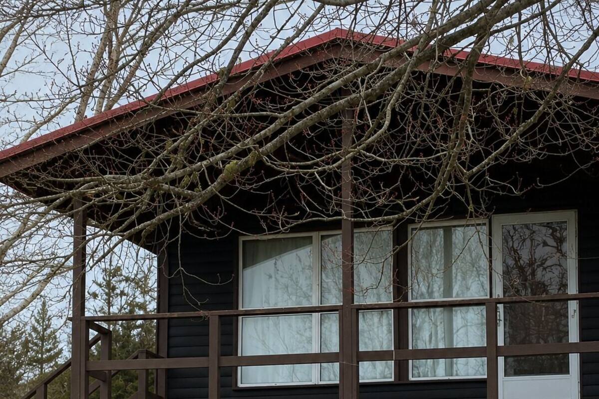 Una casa de madera de dos pisos con un porche cubierto, ventanas amplias y un césped bien cuidado.