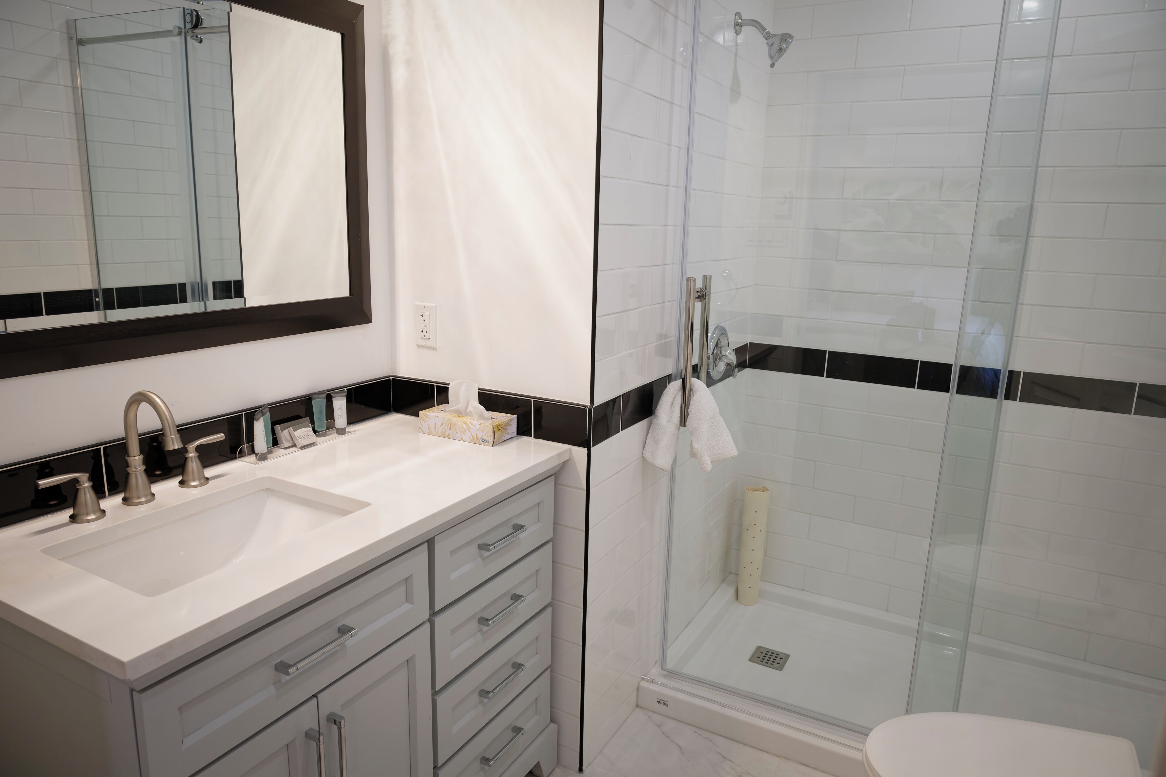 Un baño con un espejo grande, un lavabo, cabina de ducha de vidrio y un inodoro.