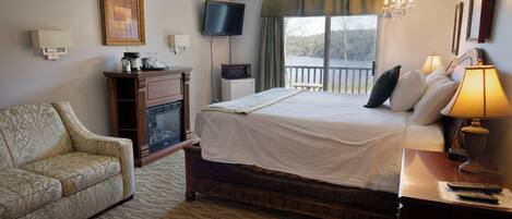 A hotel room with a bed, a television, a desk with a lamp, a chair, and a view of the outdoors.