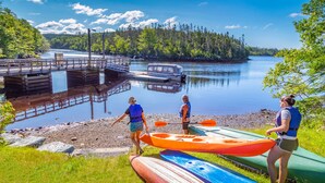A lakeside scene with a dock, kayaks, and people preparing to paddle. - Liscombe Lodge Resort and Conference Centre (Liscomb Mills)