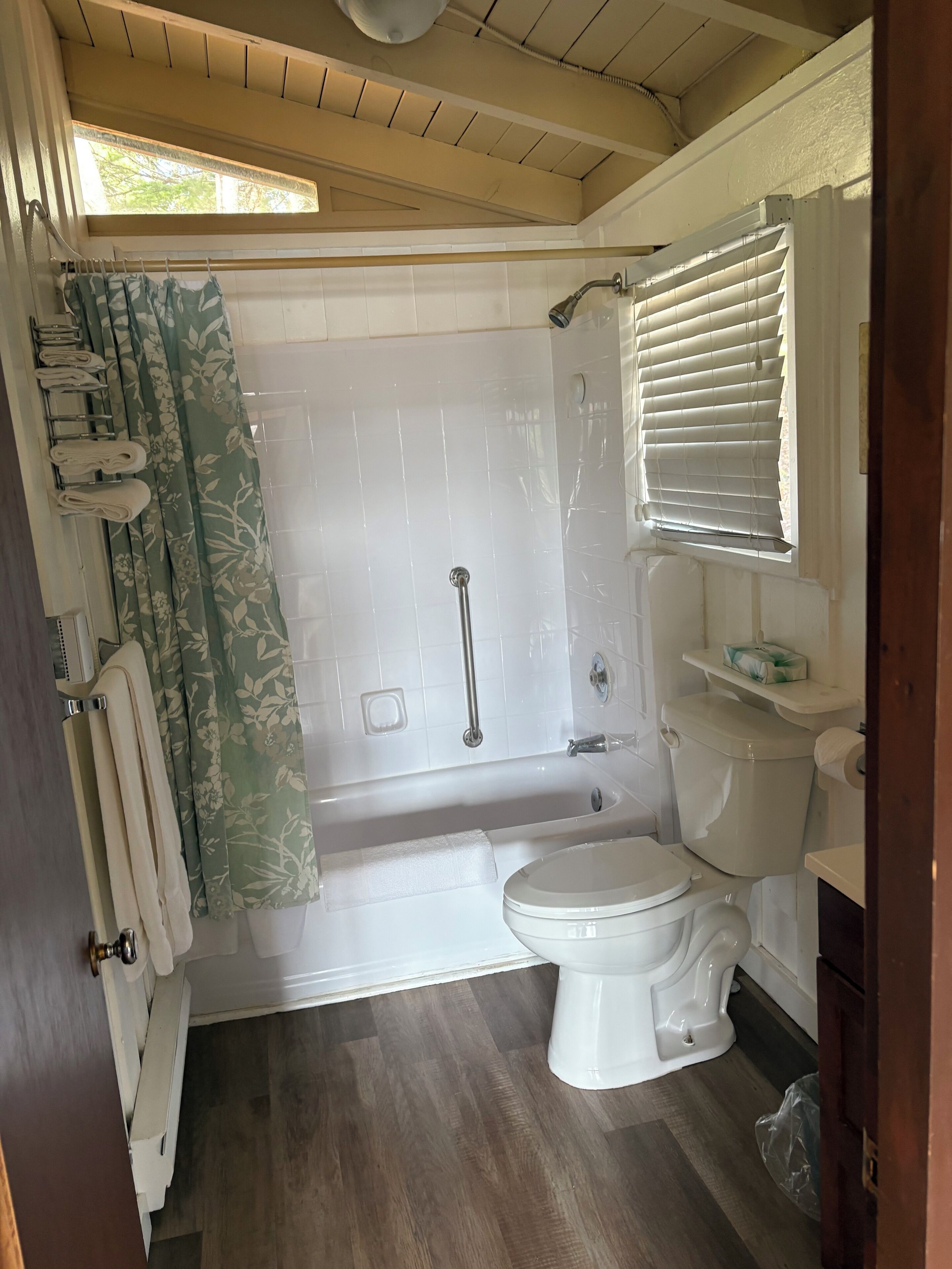 A bathroom with a bathtub, toilet, and shower area.