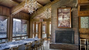 A dining area with a long table, chairs, a fireplace, and a large window. - Liscombe Lodge Resort and Conference Centre (Liscomb Mills)