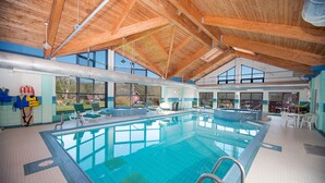 An indoor swimming pool with a high wooden ceiling, clear windows, and lounge chairs. - Liscombe Lodge Resort and Conference Centre (Liscomb Mills)