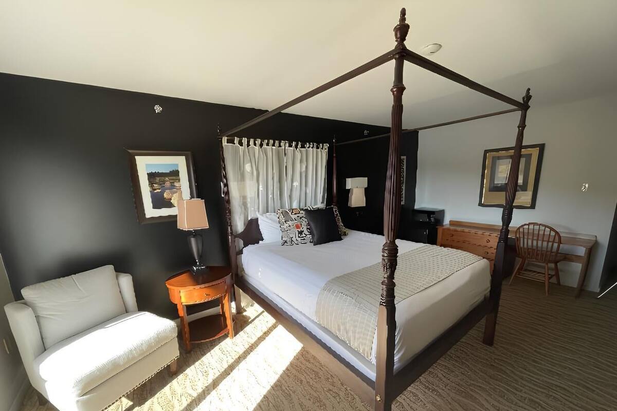 Una cama con dosel en un dormitorio con un sofá, un escritorio y una silla.