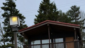 A cabin with a balcony, surrounded by trees and a well-maintained lawn. - Liscombe Lodge Resort and Conference Centre (Liscomb Mills)