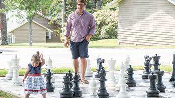Enjoy a game of chess in a serene outdoor setting with a beautifully maintained lawn.