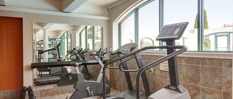 A gym with treadmills, exercise bikes, and a mirrored wall.
