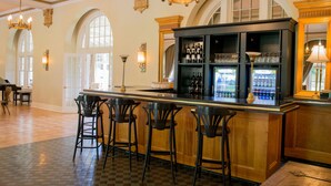A bar area with a checkered floor, wooden bar counter, and black bar stools. - Digby Pines Golf Resort and Spa (Digby)