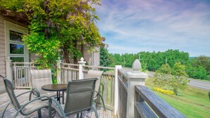 A wooden deck with outdoor furniture, a white railing, and a view of a road and greenery. - Digby Pines Golf Resort and Spa (Digby)