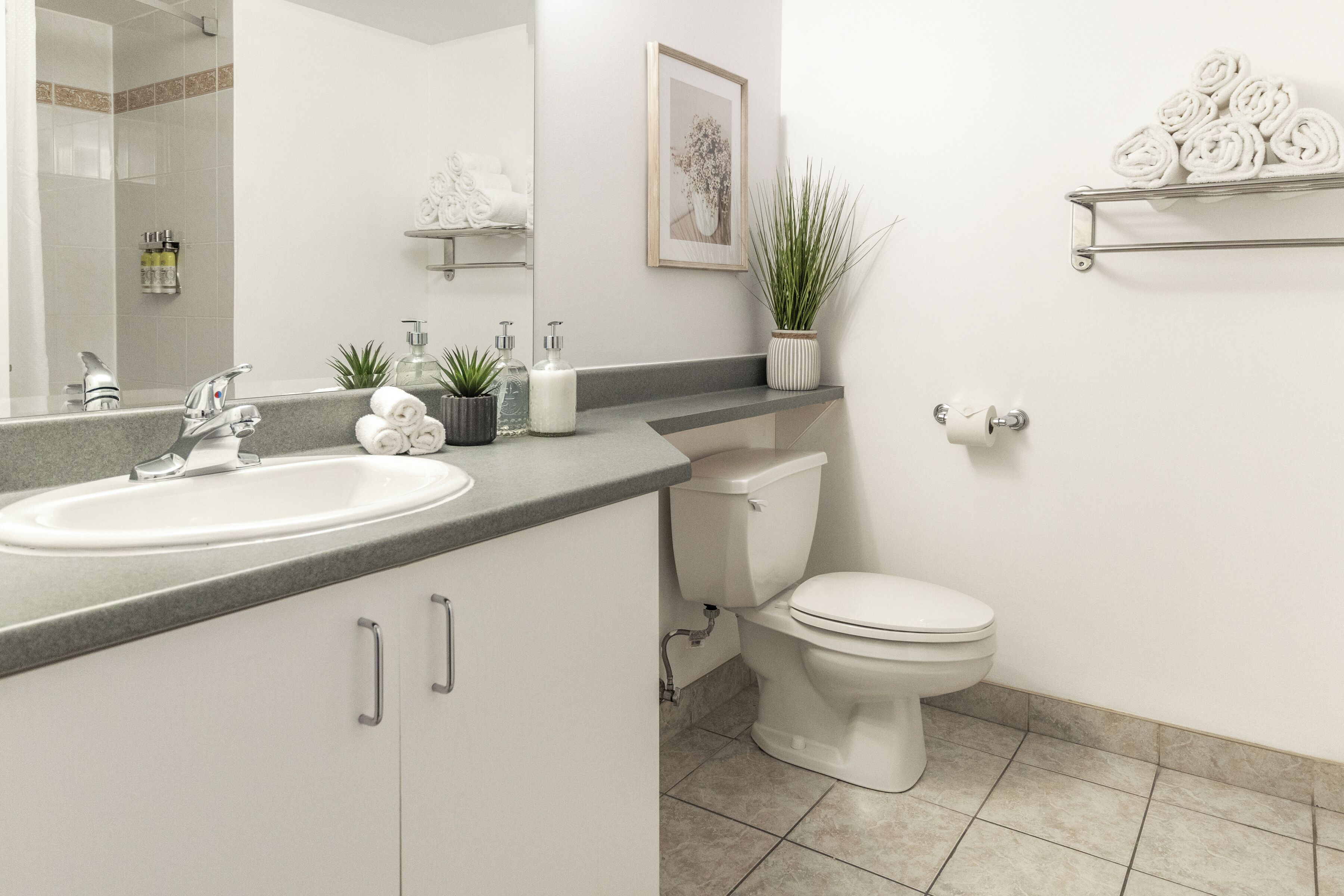 A bathroom with a sink, toilet, and a mirror. There are towels and toiletries on the counter.
