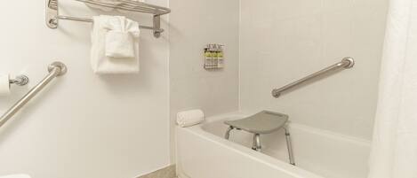 Ein Badezimmer mit Badewanne, Dusche, Toilette und Handlauf.