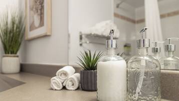 A bathroom counter with toiletries, a potted plant, and a towel rack.
