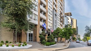 Un edificio a più piani con balconi, una bandiera e un cartello che indica un albergo.