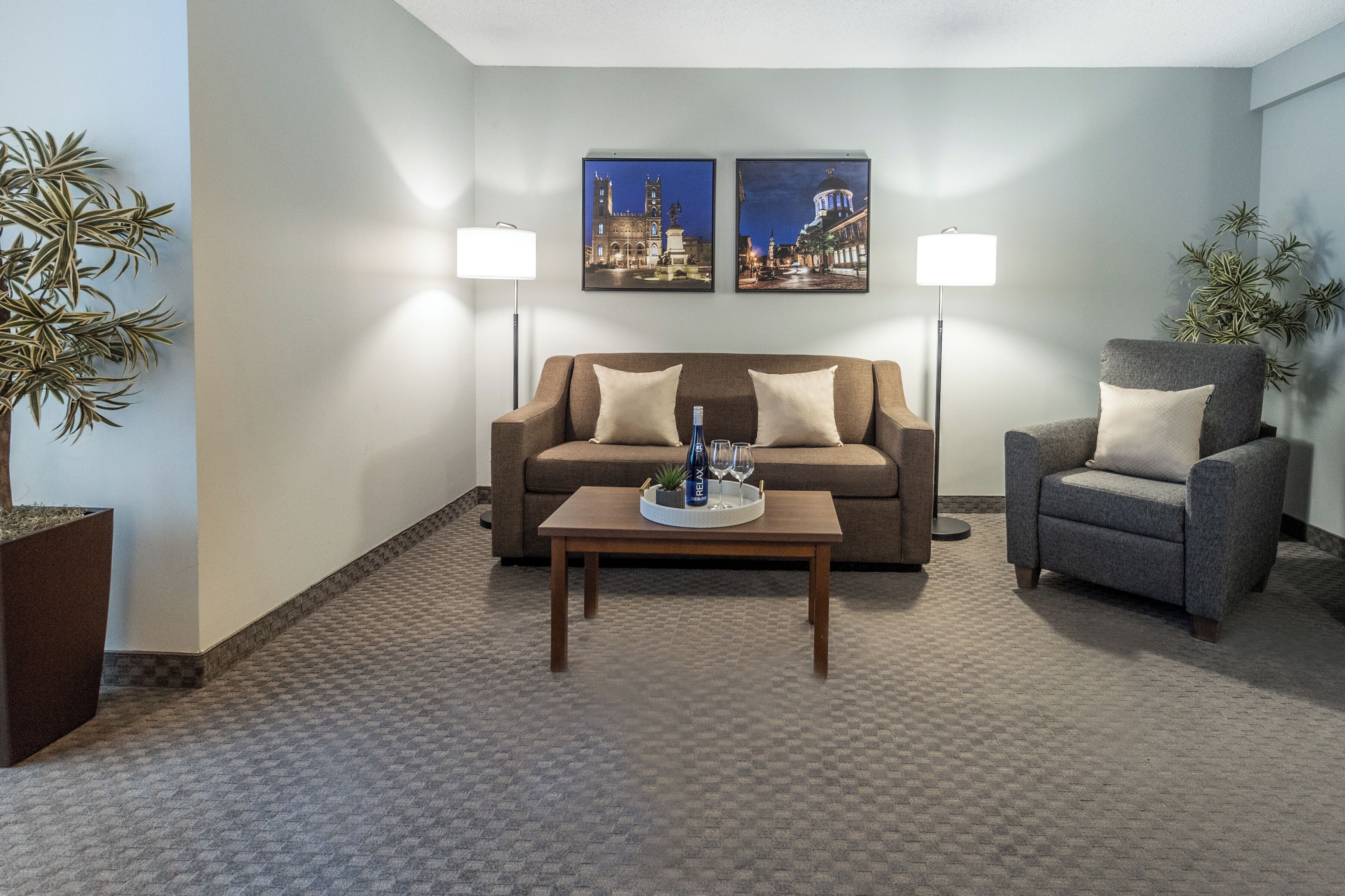 Una sala de estar con sofá, sillón, mesa de centro y dos lámparas de pared.