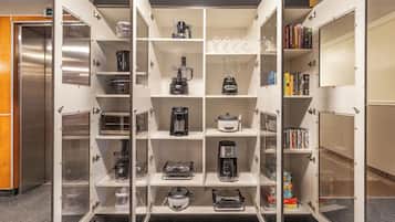 Una kitchenette con varios electrodomésticos y estantes de almacenamiento.