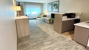 A modern hotel room with a living area, kitchenette, and a large window. - Best Western Plus Kelly Inn (St Cloud)