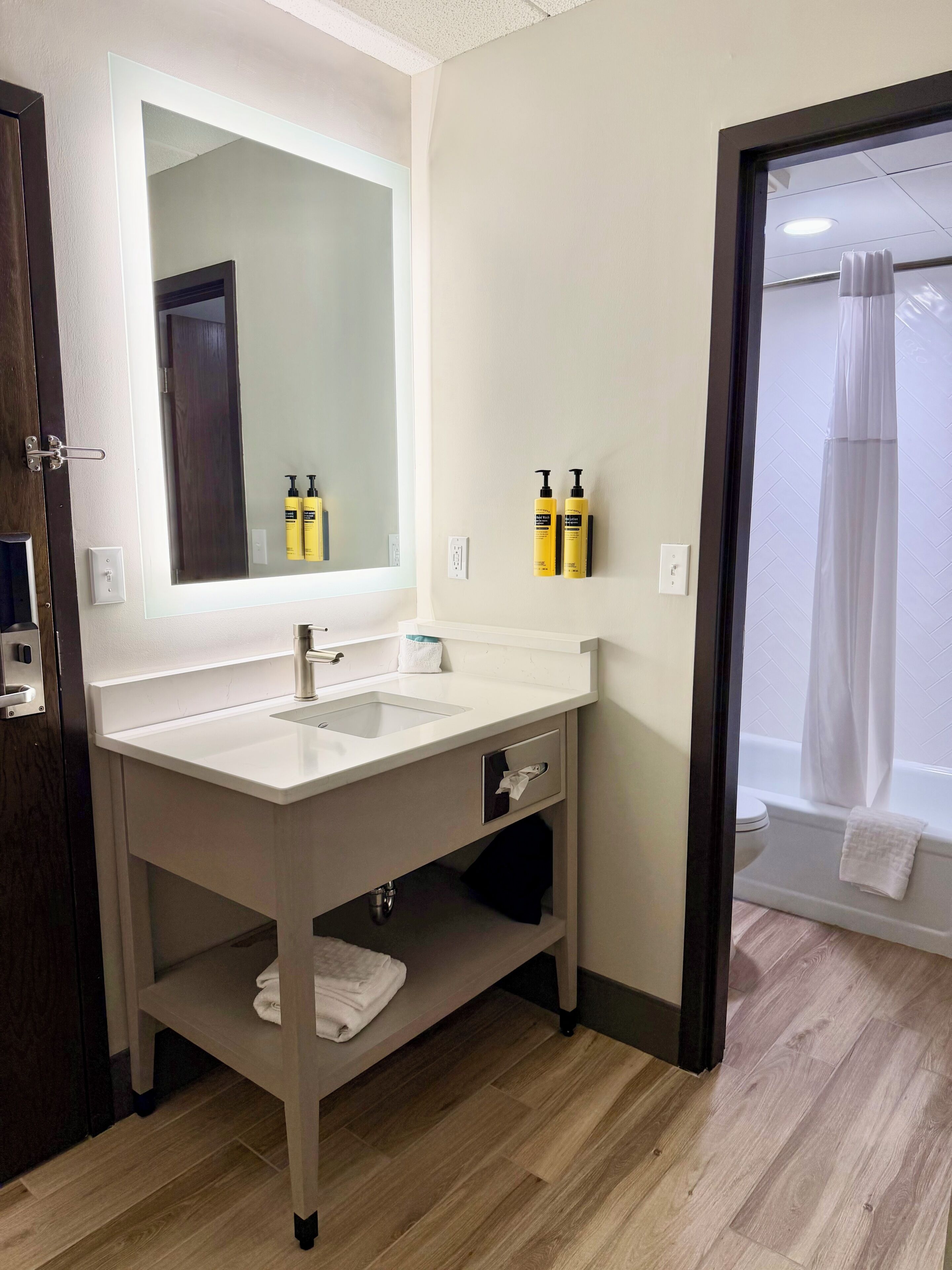 Une salle de bain avec un lavabo blanc, un miroir et deux bouteilles jaunes accrochées au mur.
