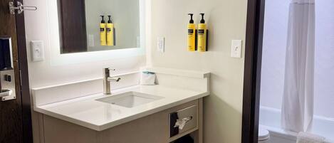 Une salle de bain avec un lavabo blanc, un miroir et deux bouteilles jaunes accrochées au mur.