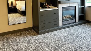 A hotel room with a large mirror, a wardrobe with drawers, a flat-screen TV, a fireplace, and a window with a view. - Best Western Plus Kelly Inn (St Cloud)
