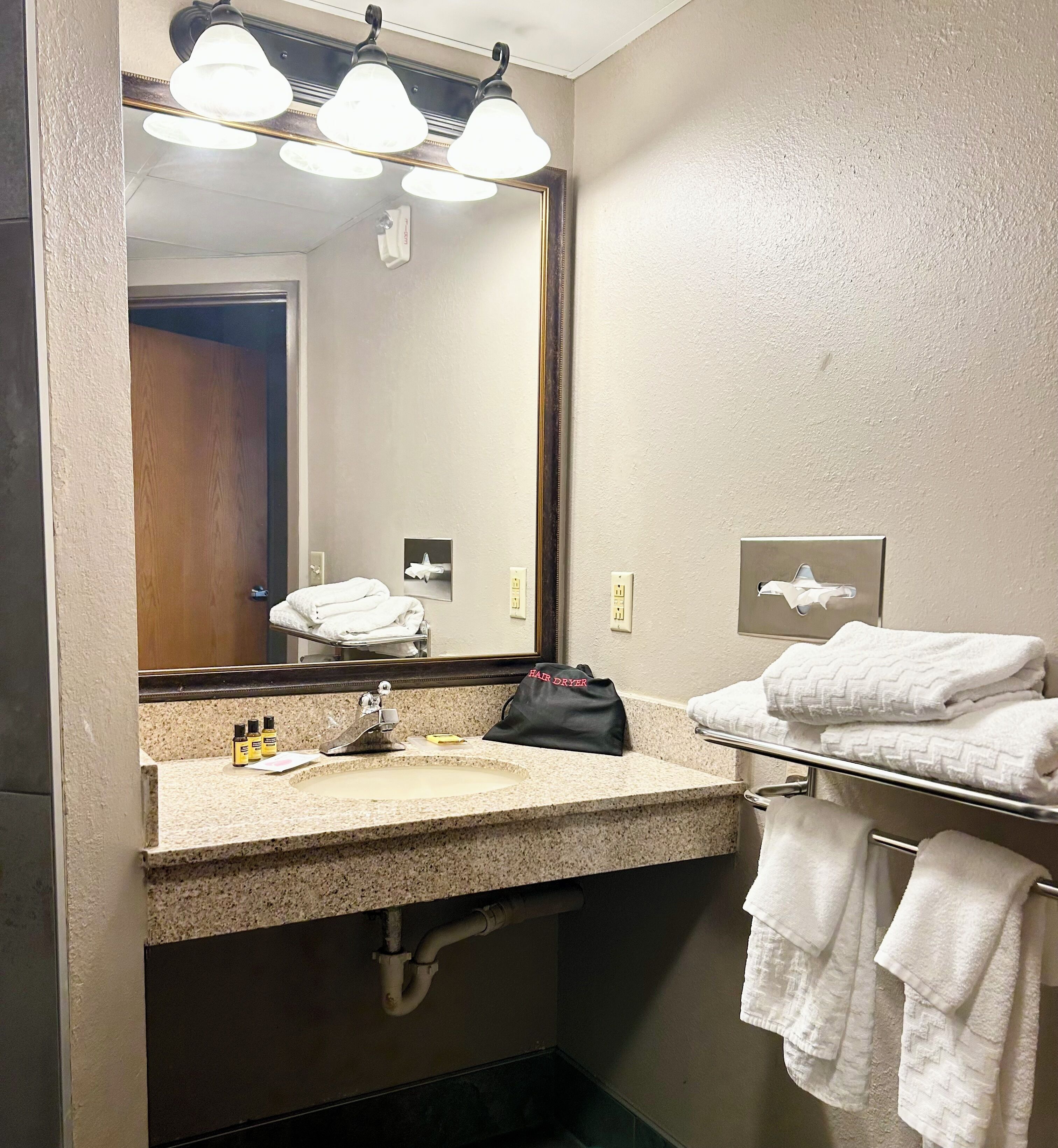 A bathroom with a sink, mirror, towel rack, and a framed picture on the wall.