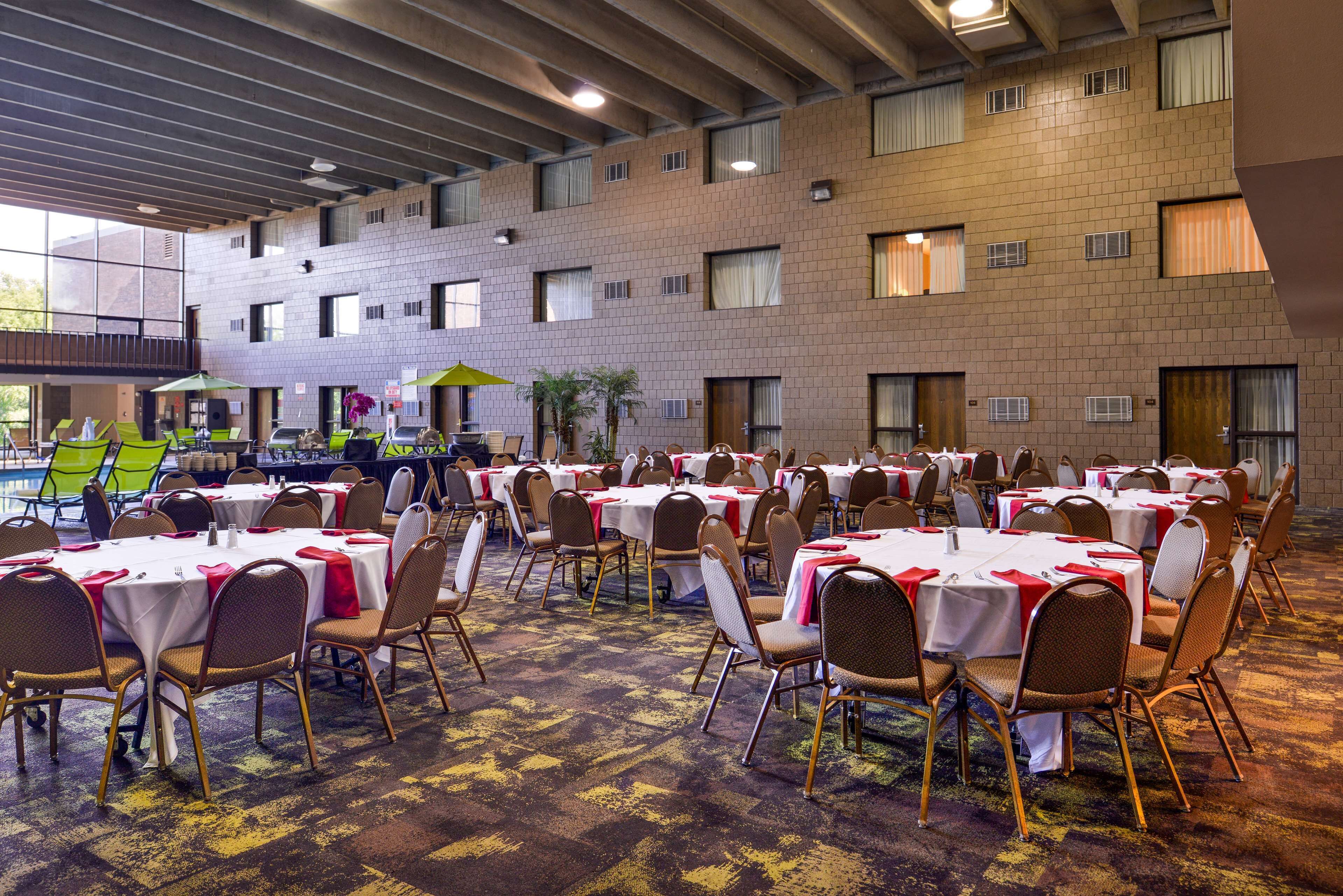A banquet hall with multiple round tables and chairs, arranged in rows.