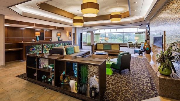 A modern hotel lobby with a reception desk, seating area, and large windows offering a view of the outdoors. - Best Western Plus Kelly Inn (St Cloud)