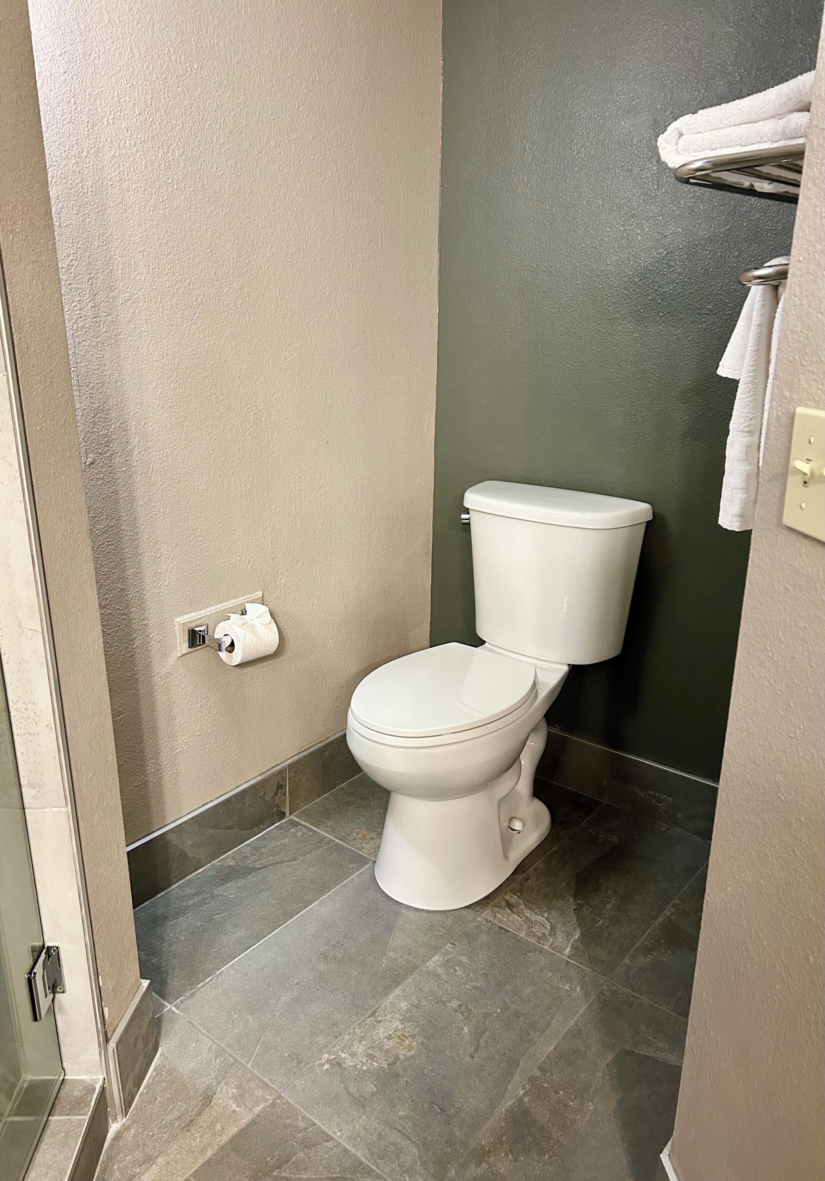A bathroom with a toilet, a towel rack, and a toilet paper holder.
