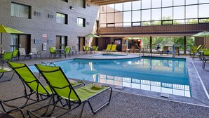 A pool area with green lounge chairs and a view of the building's interior. - Best Western Plus Kelly Inn (St Cloud)