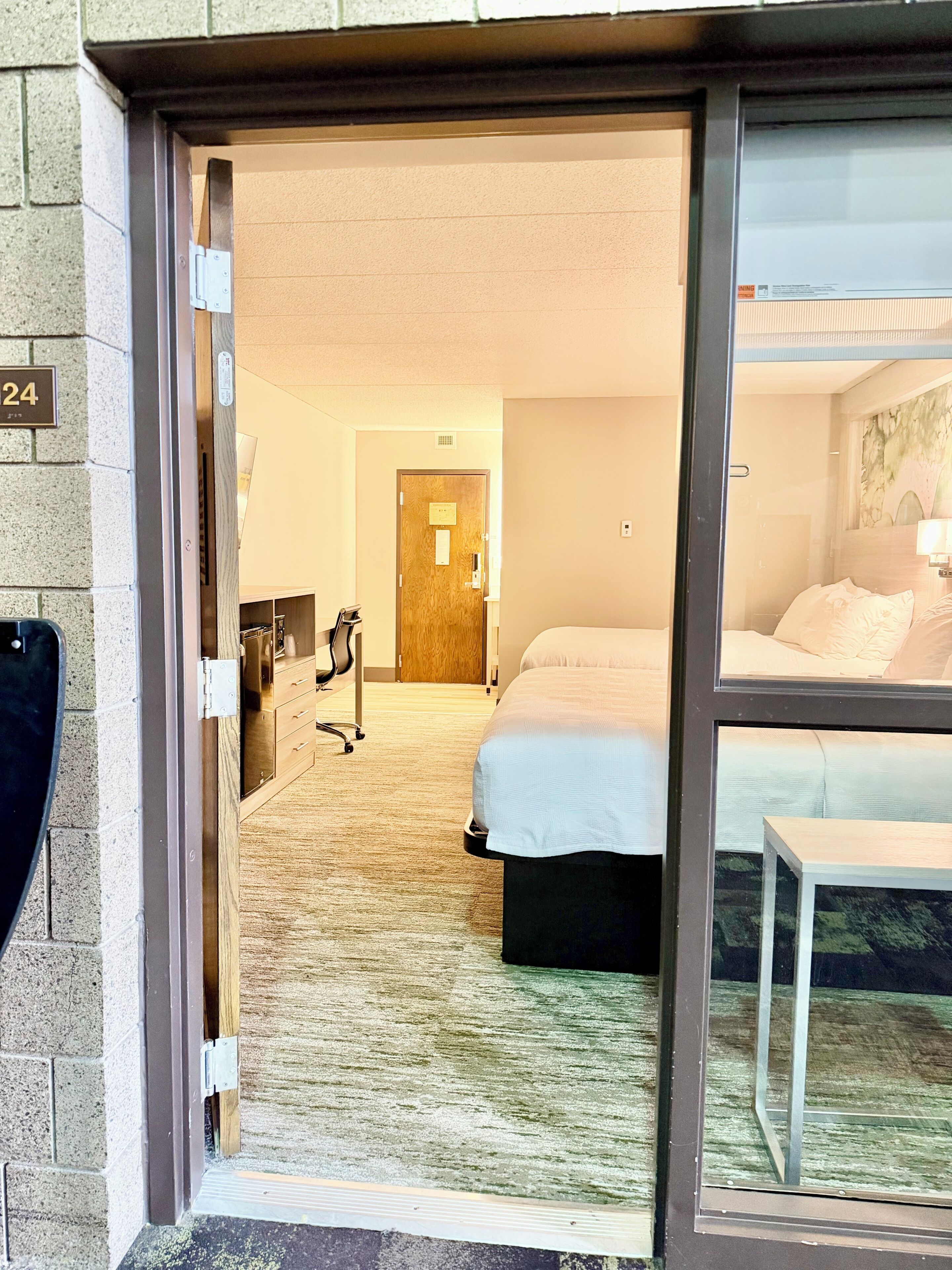 Habitación de hotel con cama, escritorio y silla. Se ve una puerta que conduce a otra habitación.