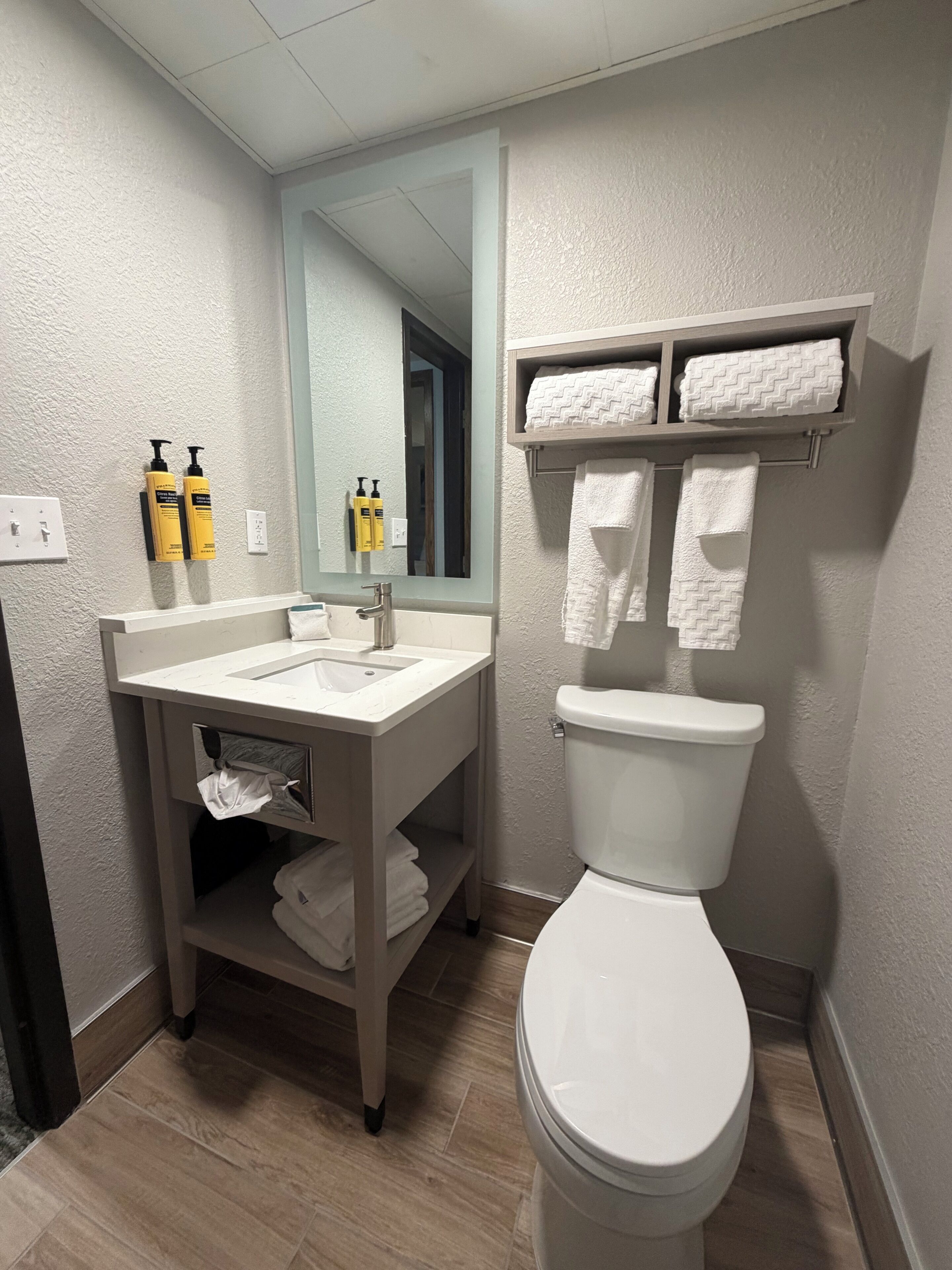 Un baño moderno con lavamanos, espejo, inodoro y toallero.