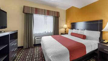 A hotel room with a bed, a desk, a lamp, and a television.