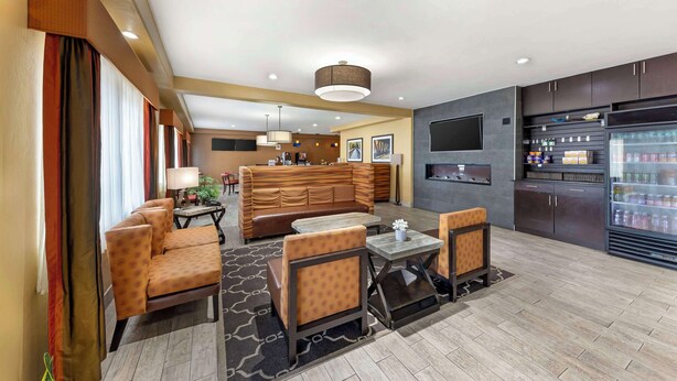 A hotel lobby with a seating area, a kitchen, and a refrigerator stocked with beverages. - Best Western Greentree Inn & Suites (Moore)